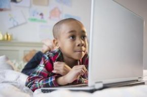 African American boy using laptop on bed - Blend Images - JGI/Jamie Grill/Brand X Pictures/Getty Images