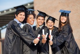 Students In Graduation Gowns Showing Diplomas On Campus